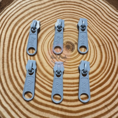 Seis pegas de fecho éclair azuis claros sobre madeira com padrão circular