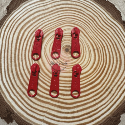 Seis cursoras de zíper vermelhas sobre um fundo de madeira com anéis concentricos