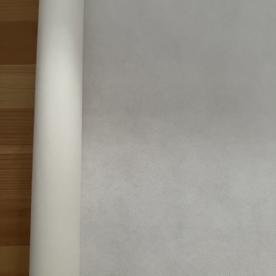 Rolo de papel branco com textura fina sobre superfície de madeira clara