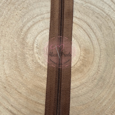 Fecho éclair castanho com padrão ziguezague sobre madeira clara