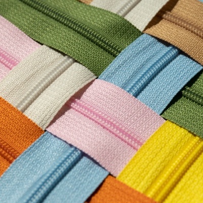 Vários fechos éclair coloridos entrelaçados formando um padrão cruzado.