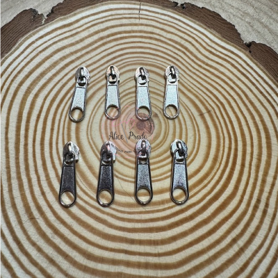 Oito carrinhos metálicos para fechos de correr sobre superfície de madeira redonda