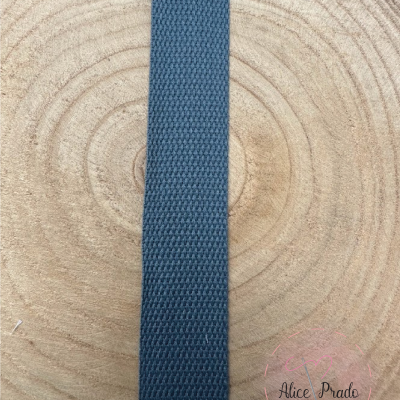 Fita de tecido azul escura com textura entrelaçada sobre madeira clara com anéis