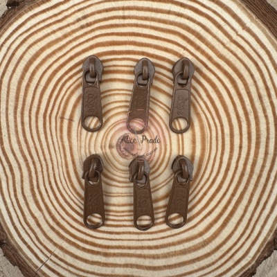 Seis cursores de zíper castanhos escuros sobre superfície com padrão de anéis de árvore