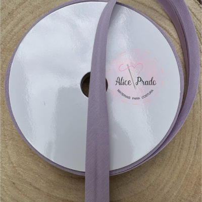 Rolo de fita lilás sobre superfície de madeira com etiqueta central branca