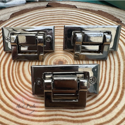 Três fechos metálicos prateados sobre superfície de madeira com padrão de anéis.