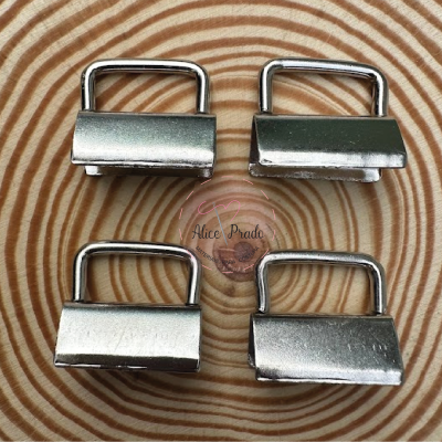 Quatro fechos metálicos prateados sobre superfície de madeira com padrão de anéis