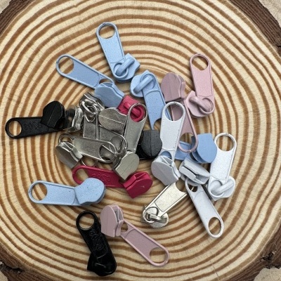 Puxadores de zíper coloridos com laço em tecido sobre madeira.