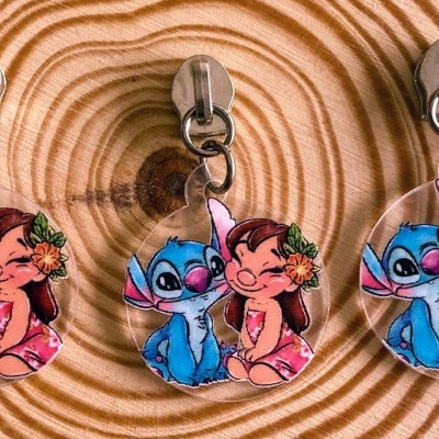 Três porta-chaves com ilustração de personagens coloridos pendurados em madeira clara