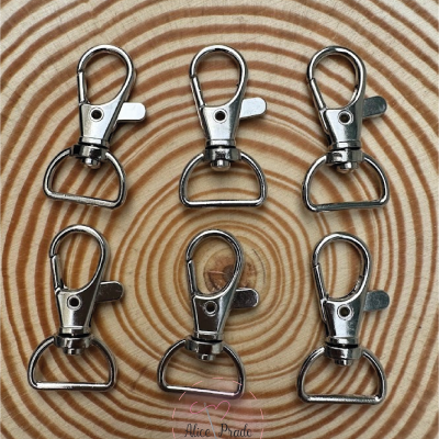 Seis mosquetões metálicos prateados sobre madeira com anéis concêntricos