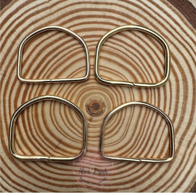 Quatro argolas metálicas douradas sobre superfície de madeira com padrão circular