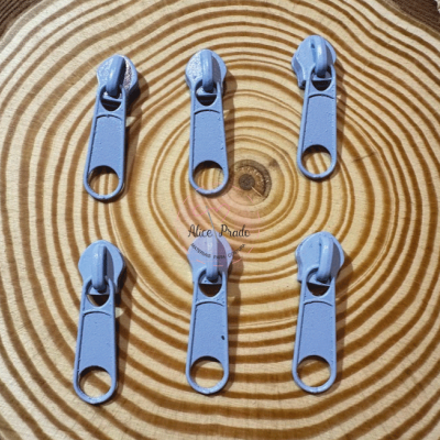 Seis puxadores de fecho éclair azuis sobre fundo de madeira com anéis concêntricos.