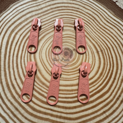 Seis puxadores de fecho éclair cor-de-rosa sobre superfície de madeira com anéis