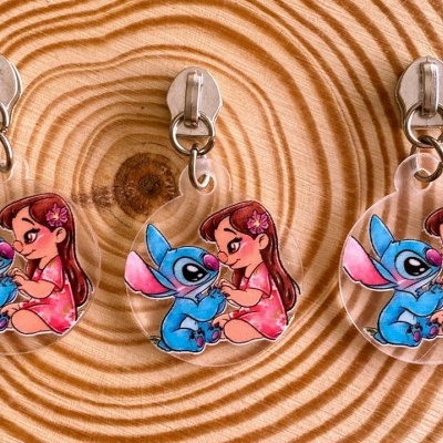 Porta-chaves acrílicos com desenhos de rapariga e personagem azul sobre madeira