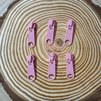 Seis puxadores de fecho éclair cor-de-rosa sobre superfície de madeira com texto