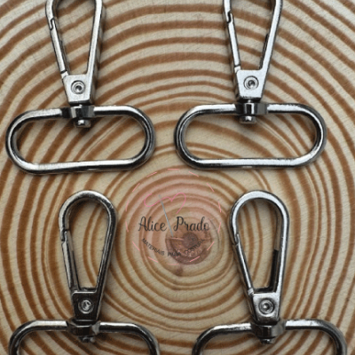 Quatro mosquetões metálicos prateados sobre madeira com padrão de anéis