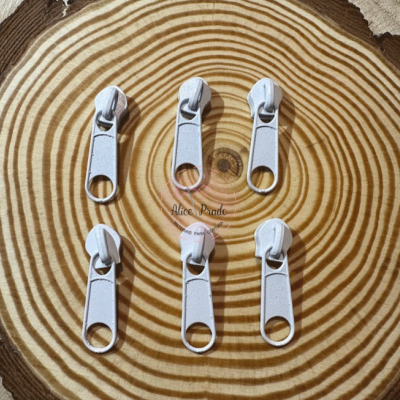 Seis cursores de zíper brancos sobre madeira clara com textura em anéis