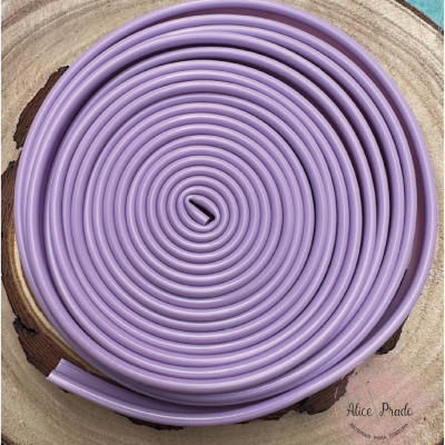 Cordão lilás enrolado em espiral sobre superfície de madeira com texto Alice Prado