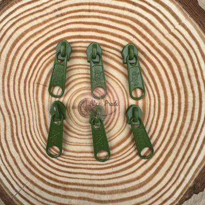 Seis puxadores de fecho verdes sobre superfície de madeira com anéis concêntricos