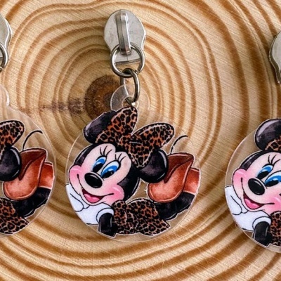 Três chaveiros Minnie Mouse em padrão animal print sobre madeira clara