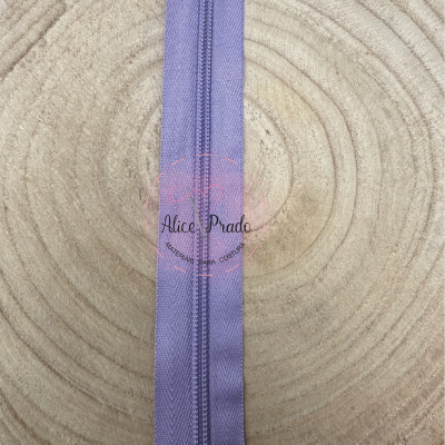 Fecho éclair lilás sobre superfície de madeira com textura concêntrica