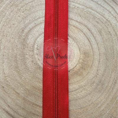 Fita de tecido vermelha com costura central sobre superfície de madeira clara