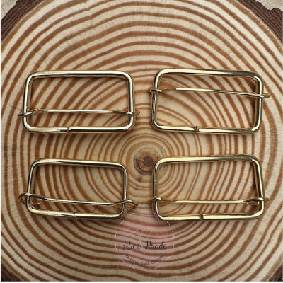 Quatro fivelas douradas retangulares em madeira com padrão circular.