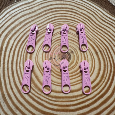 Oito pegas de fecho éclair cor-de-rosa sobre tronco de madeira