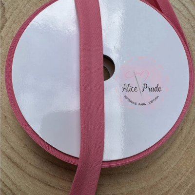 Rolo de fita cor-de-rosa com etiqueta Alice Prado sobre madeira