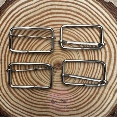 Quatro fivelas metálicas prateadas sobre superfície com padrão de madeira