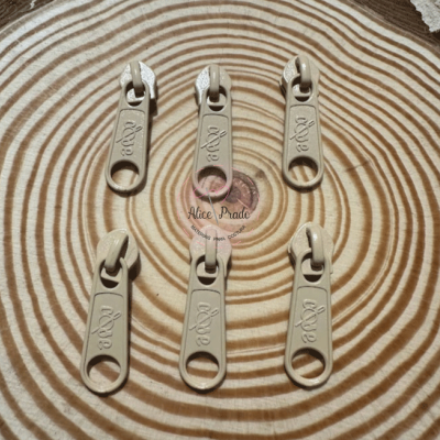 Seis pegas de fecho éclair bege sobre superfície de madeira com padrão de anéis