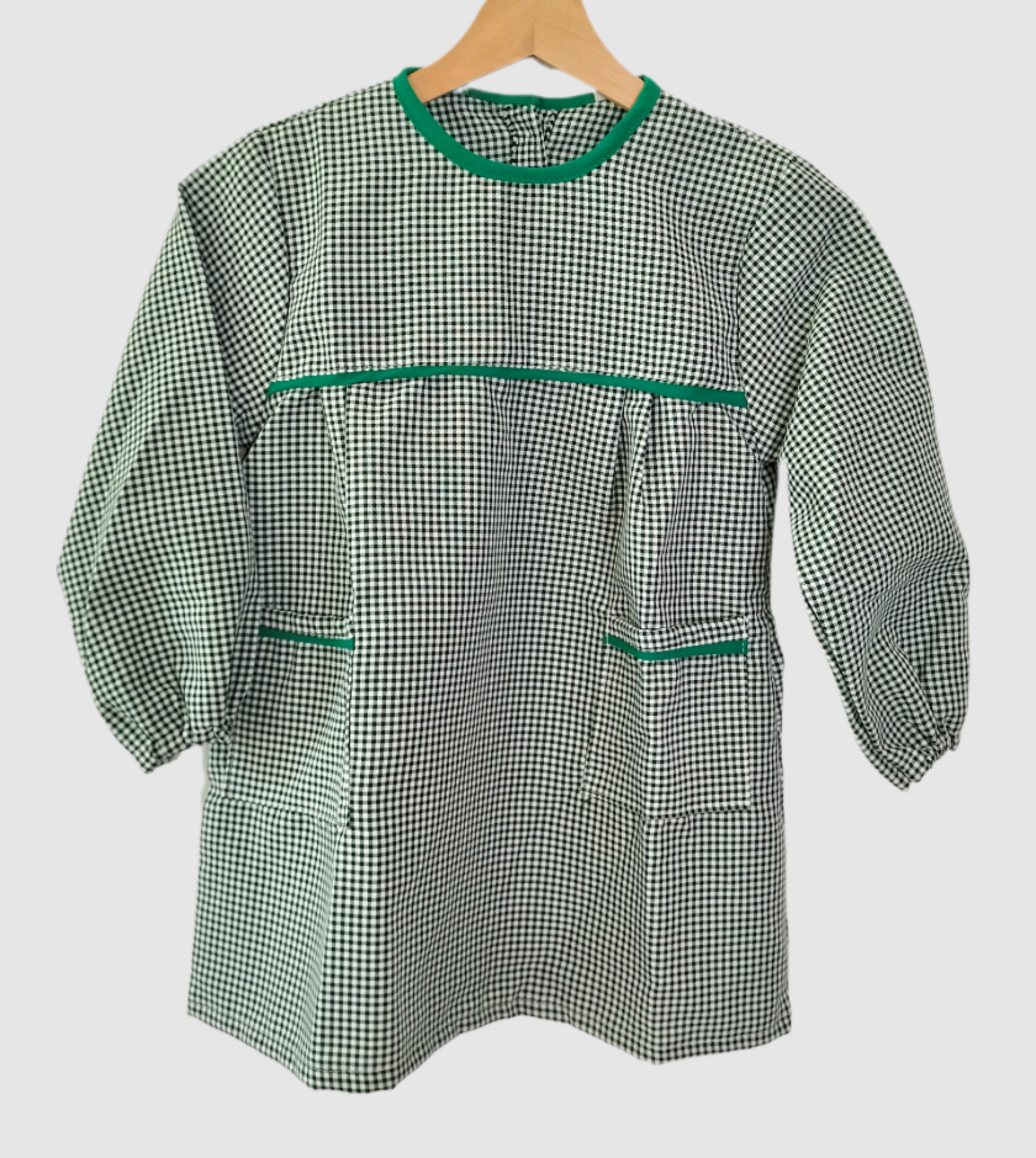Bata escolar menina verde Casaco xadrez verde e branco com detalhes verdes pendurado num cabide
