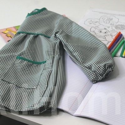 Casaco infantil xadrez verde branco sobre cadernos e materiais de desenho