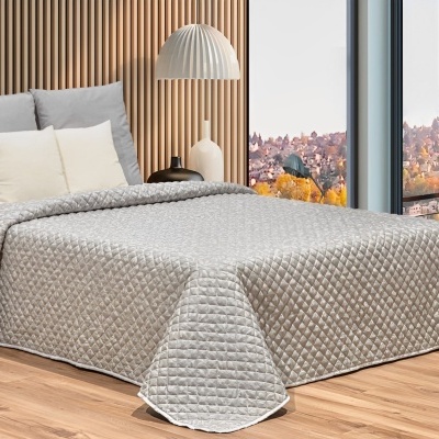 Cama com edredão cinza acolchoado, almofadas, abajur e parede de madeira