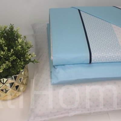 Conjunto roupa de cama azul claro com padrão, almofada e vaso decorativo com planta