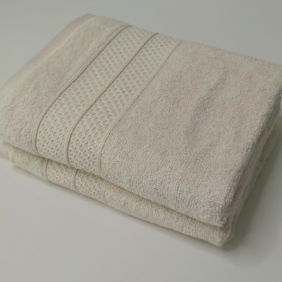 Toalhas de banho creme com padrão texturizado e liso.