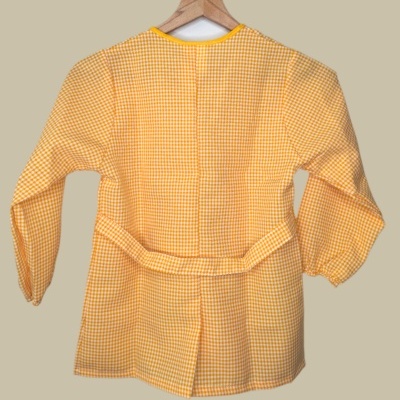 Blusa amarela com padrão quadriculado branco em cabide de madeira