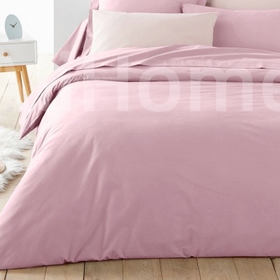 Cama com roupa de cama rosa claro, mesa de cabeceira branca e tapete felpudo branco