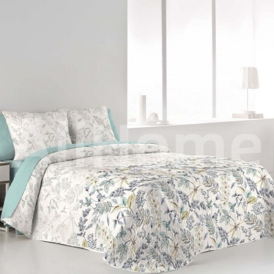 Cama com conjunto de roupa de cama floral azul e verde sobre fundo branco, lençol azul acolchoado, quarto minimalista