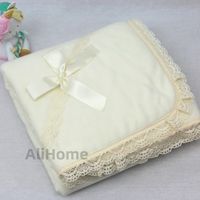 Manta cremosa com renda bege e brinquedo colorido ao lado