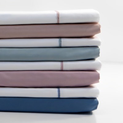 Pilhas de lençóis dobrados em várias cores pastéis com faixas de cor na borda.