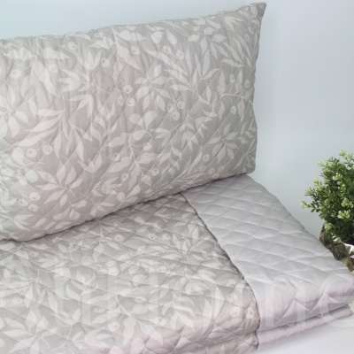 Conjunto de almofada e edredão bege com padrão floral e vaso de planta verde