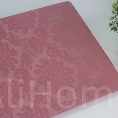 Capa têxtil rosa com padrão floral ao lado de vaso prateado com plantas