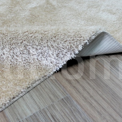 Tapete felpudo creme claro sobre chão de madeira clara