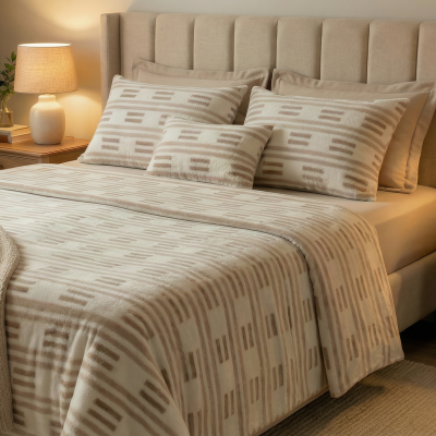 Cama com conjunto têxtil creme e bege e cabeceira estofada, mesas de cabeceira em madeira com candeeiros e plantas.