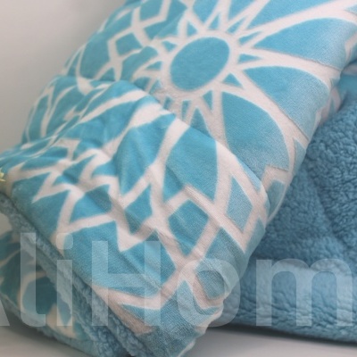 Manta azul clara com padrão azul e branco dobrada perto de um vaso com planta verde