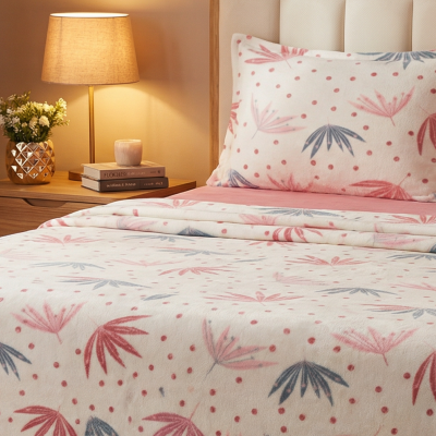 Conjunto de cama com padrão de folhas e mesa de cabeceira com lâmpada e flores