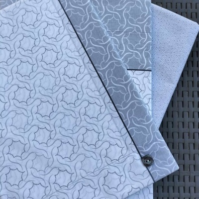 Toalhas brancas e cinzas com padrões geométricos e botões pretos sobre superfície escura