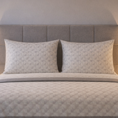 Cama com roupa de cama cinza com padrão geométrico e abajures em mesas de cabeceira de madeira