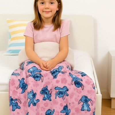 Menina numa cama com manta cor-de-rosa estampada de Stitch